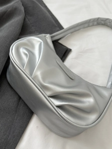 Sac à bandoulière argenté plissé en forme de croissant avec logo sur fond gris