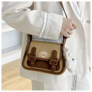 Détail du sac à bandoulière bicolore avec broderie de chien et pendentif en peluche