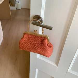 Close-up of orange beaded evening bag with shell shape and golden metal handles