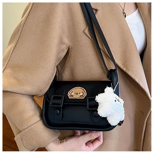 Détail d'un sac bandoulière vintage noir avec patch ours et pendentif mouton pelucheux