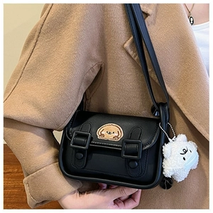 Détail du mini sac noir avec écussons de dessin animé et breloque nuage en peluche