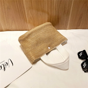 Detail of hand-woven straw tote with white canvas handles and snap closure button