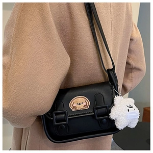Détail du sac bandoulière vintage en cuir noir avec pendentif ours et écusson