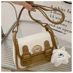 Détail du sac en cuir bicolore avec broderie chien et breloque ours en peluche
