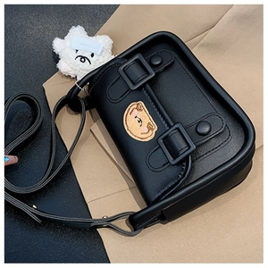 Gros plan d'un mini sac noir avec écusson ours jaune et pendentif étoile en peluche douce