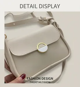 Detailed macro view of cream leather shoulder bag featuring a unique gold circular buckle