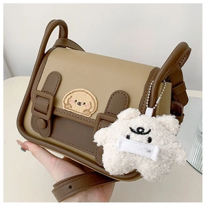 Détail d'un sac bicolore avec broderie animale et breloque en peluche sur le côté