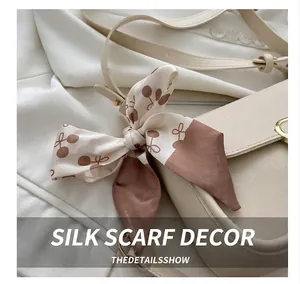Detail of cream leather bag with silk polka dot scarf and golden ring hardware