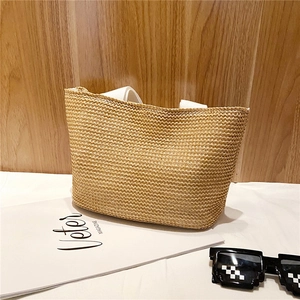 Detail of hand-woven straw tote bag with sturdy white fabric handles for beach vacation