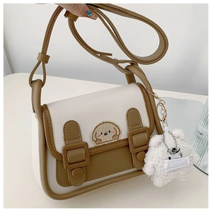 Détail du sac bandoulière bicolore avec broderie chiot et pendentif ours en peluche