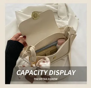 Detail view of cream shoulder bag open compartment showing storage space with silk scarf
