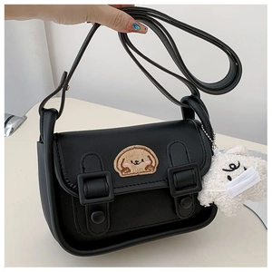 Détail du sac en cuir noir avec broderie de chien brun et breloque étoile en peluche