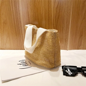 Detail of hand-woven straw tote with white canvas handles for summer beach vacations