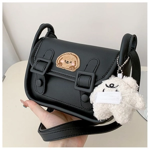 Détail d'un sac bandoulière en cuir noir avec patch chien et breloque en peluche
