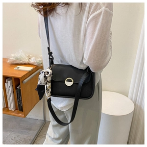 Detail of black leather crossbody bag featuring a golden buckle and stylish silk scarf