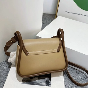 Détail d'un sac à bandoulière en cuir contrasté avec pompon doux et surpiqûres