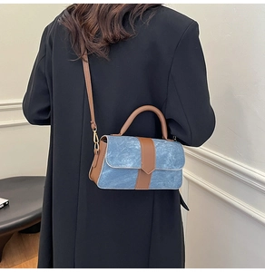 Detail van de blauwe denim en bruine leren crossbodytas gedragen door een model