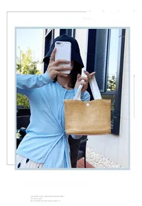 Detail view of woven straw tote bag featuring white wide straps and secure resin buckle