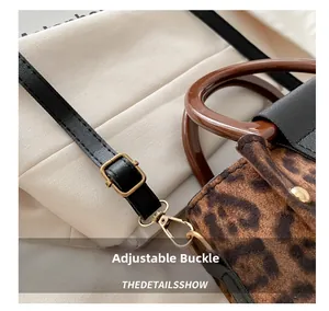 Détail du sac léopard avec boucle dorée et bandoulière en cuir noir réglable
