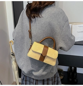 Detailweergave van de patchwork crossbodytas met bruin handvat en beige getextureerd leer