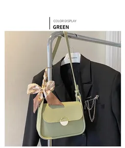 Detail view of light green flap bag with printed silk scarf and gold buckle