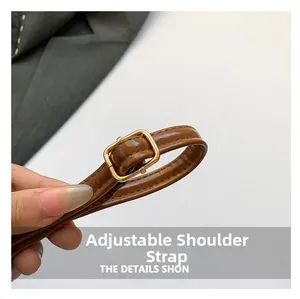 Detail of adjustable brown leather strap with polished gold metal buckle for handbag