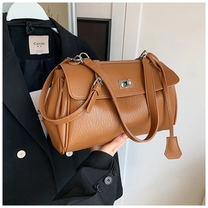Close-up of brown lychee grain leather handbag with metal turn-lock and key charm