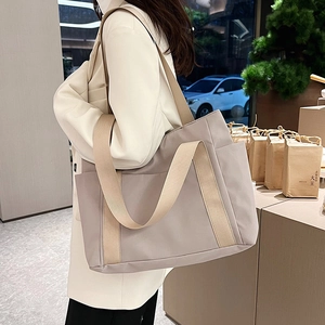 Detail of a large nylon tote bag featuring wide shoulder straps and side pocket detail