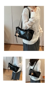 Detail of black glossy shoulder bag with CLEARDX logo and heart tassel pendant
