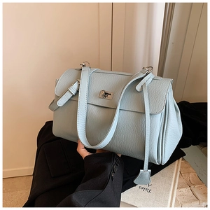 Detailed view of light blue textured leather shoulder bag with a silver metal twist lock