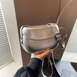Gros plan sur un sac besace argenté avec bandoulière réglable et détails cloutés