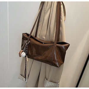 Detail of brown leather shoulder bag with vintage finish and baseball theme keychain