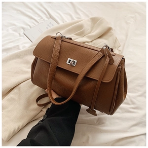 Close-up of brown litchi pattern leather underarm bag with silver twist lock and handle