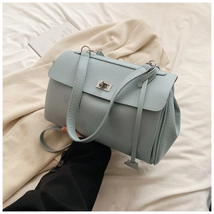 Detail of light blue lychee pattern leather shoulder bag with metal turn lock and tassel