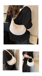 Close-up of white crescent bag with front pockets and metallic adjustable buckle