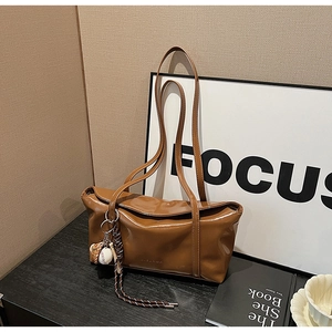 Detail of glossy brown leather shoulder bag with baseball charms and embossed logo