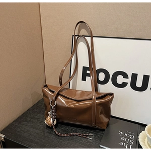 Detail of dark brown glossy leather shoulder bag with creative baseball glove charm