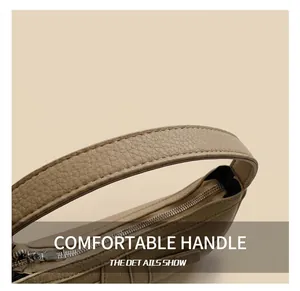 Detail of the litchi grain leather strap and silver zipper on the beige crescent bag
