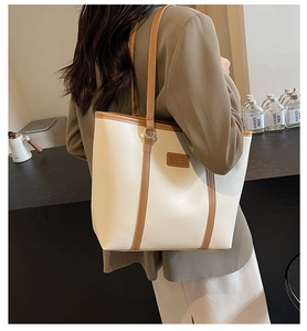Detail view of large contrast faux leather tote bag with brown straps and white body