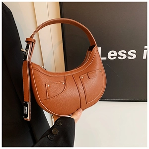 Detailed close-up of brown litchi grain leather crescent bag with decorative pockets