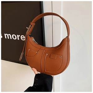 Close-up of brown crescent bag with pebble leather texture and metallic stud details