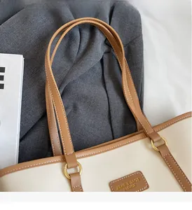 Detail of sturdy leather handles and golden metal rings on a beige tote bag