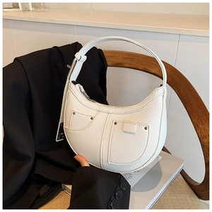Detail of white lychee leather crescent bag with silver rivets and asymmetric pockets