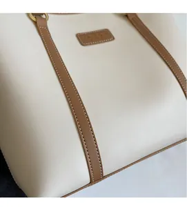 Close-up of litchi textured off-white tote bag with brown trim and gold ring details
