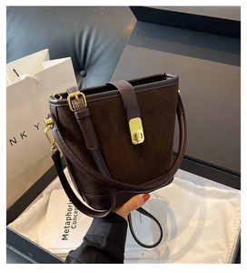 Detail view of a vintage dark brown suede bucket bag with leather trim and gold hardware