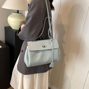 Light blue faux leather flap shoulder bag with silver turn-lock clasp shown on a model