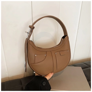 Detail of brown faux leather crescent bag with lychee texture and rivet pockets
