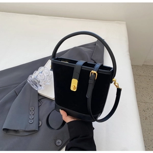 Detailed view of black suede bucket bag with gold hardware and leather strap
