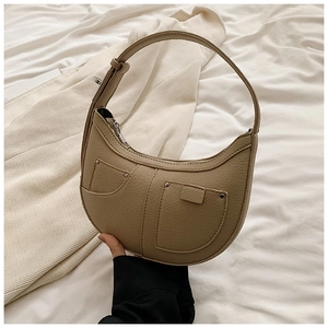 Detail view of khaki crescent bag with pebble leather texture and silver rivet pocket