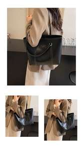 Detail of black tote bag featuring white contrast stitching and minimalist logo plate